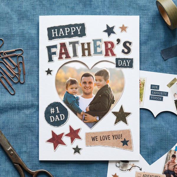 Father's Day card with a heart shaped cut out in the centre. Behind this is a photo of a man and two children. There is scrapbook style cut out letters which spell out Happy Father's Day printed on the front of the keepsake card. It also says #1 Dad and we love you on pieces of torn paper which are printed to look like a scrapbook. The front of the token keepsake card also has a few stars which look like they have been cut out and stuck on.